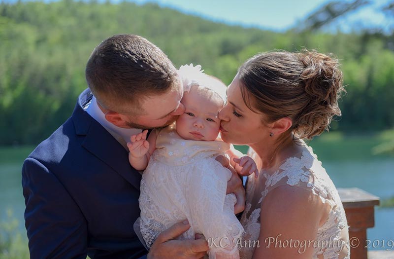 Bride and groom kissing baby
