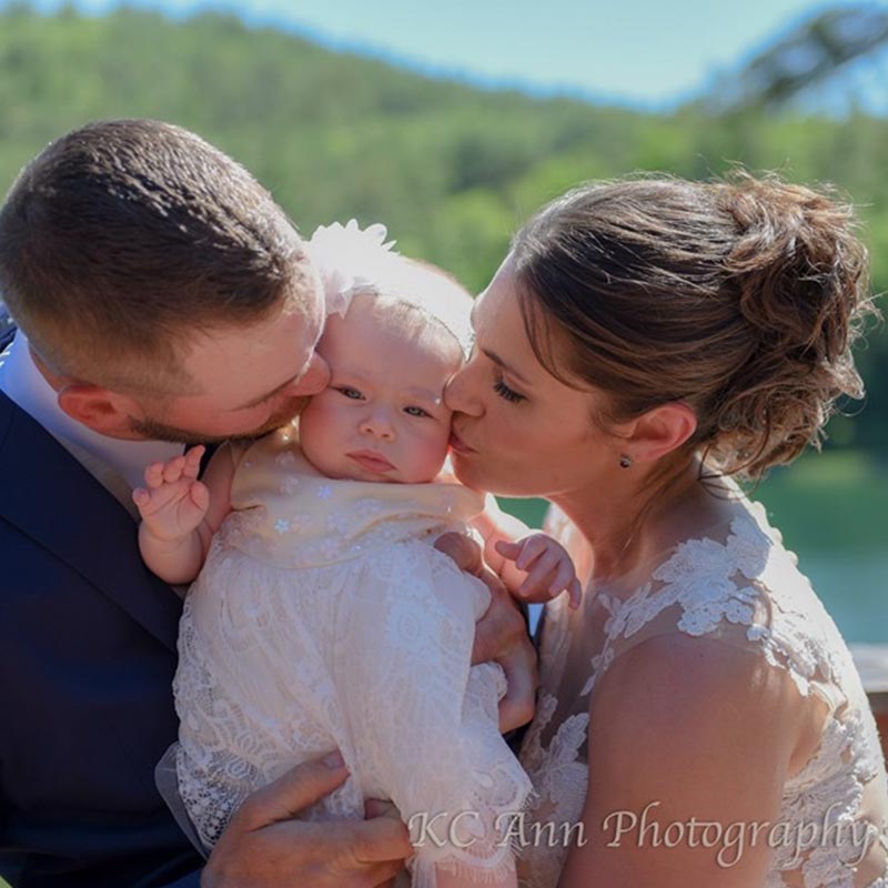 Bride and groom holding and kissing baby